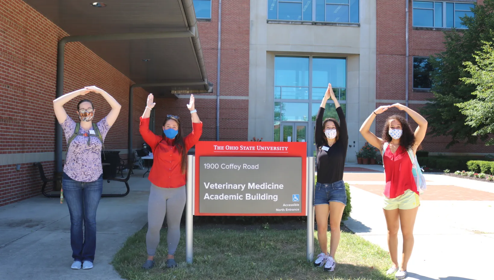 Four students posing in front of the Veterinary Medicine Academic Building sign