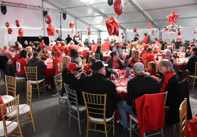 homecoming tailgate in a tent full of tables with scarlet balloons above