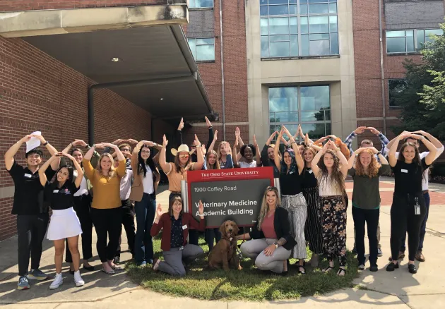 large group of students holding up O-H-I-O outside of the Veterinary Medicine building