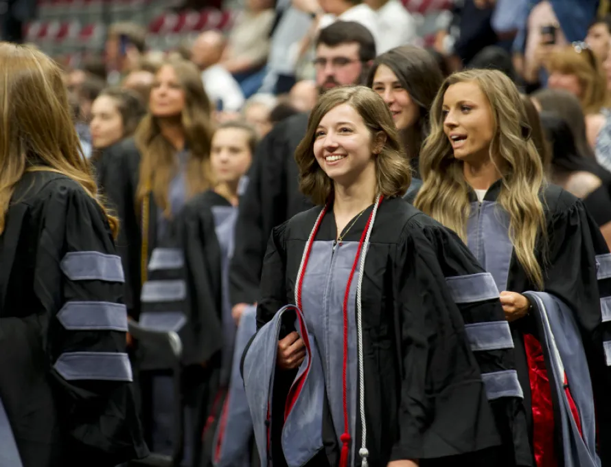 Student striding confidently forward at Oath and Hooding 2023