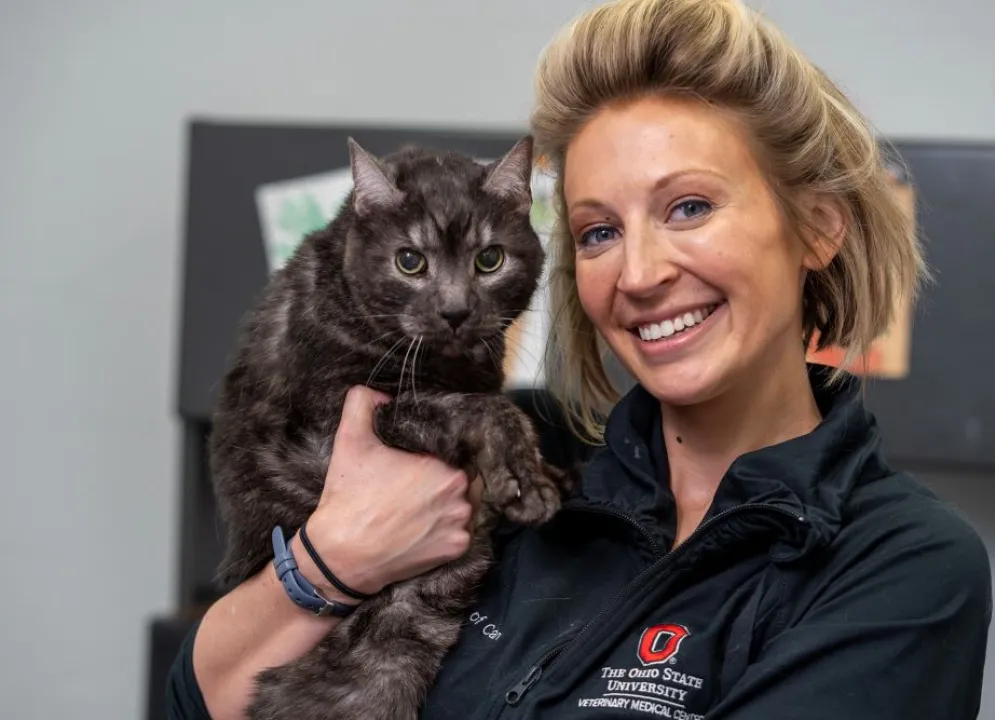 Missy Matusicky, faculty member, with her cat, sitting at her desk