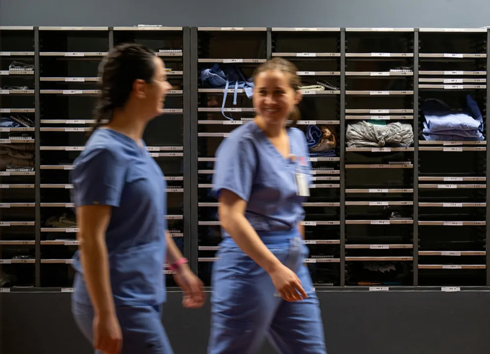 two female veterinary students smiling and walking by mailboxes