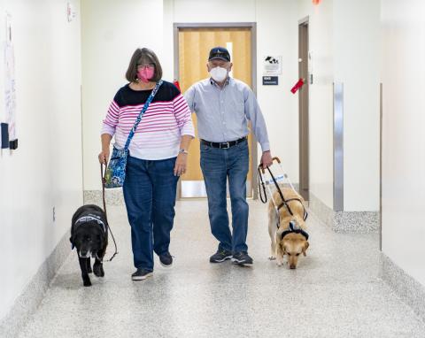 Dog owners walking out of the exam room with their service dog