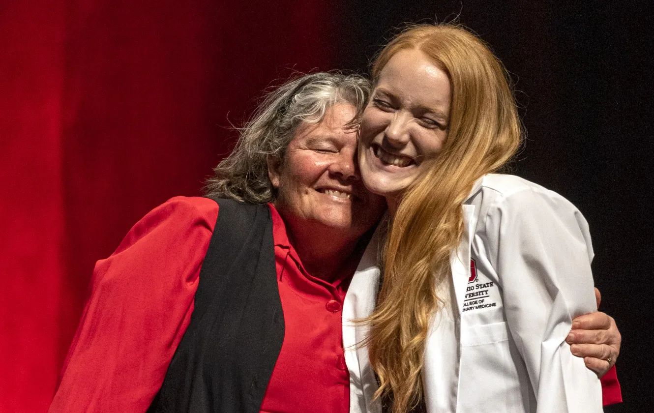 woman hugging student who just received her white coat
